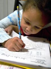 Aisha Jones, 6, concentrates on her reading homework at her home in Bolingbrook, Ill., Feb. 15, 2006. Though Aisha scored well on her annual tests, her mother, Toia Jones, a school teacher of 12 years, says she is concerned that a loophole in the No Child Left Behind Act is enabling states and schools to avoid taking concrete measures to eliminate an "achievement gap" between white and minority students.