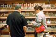 Centro Cigars owner Rich Spangler assists customer Kristen Sanders make selections from the store humidor.