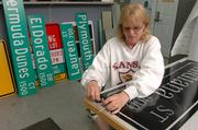 Debbie Rollins, a traffic control technician with the city's Public Works Division, finishes up a street sign earlier this week. Rollins creates many signs from start to finish for the city.