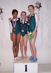 Twizters Nicole Vanahill, Madison Bennett and Blaire Landon pose on the medal stand after competing in the Kansas/Oklahoma State Tumbling/Trampoline Competition on Saturday at Washburn Rural Middle School.