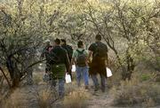 Migrants walk with bottles of water shortly before nightfall as they cross the desert between Sasabe, Mexico, and Sasabe, Ariz. Increased patrols along stretches of the border are pushing migrants into increasingly dangerous terrain.