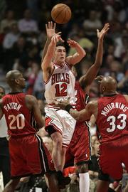 Chicago's Kirk Hinrich, center, releases a pass between Miami's Gary Payton, left, and Alonzo Mourning. The Heat won, 113-96, on Thursday night in Chicago to knock the Bulls out of the playoffs.