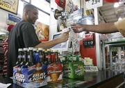 Lucien Geldrich, left, checks a customer's ID as he rings up a purchase Wednesday at the Frugal MacDoogal Beer Warehouse in Nashville, Tenn. The Tennessee House on Thursday approved a bill that would require everyone to show proof of legal age in order to buy beer. But people buying wine or liquor won't face the same ID requirement, prompting questions about how much the measure will cut underage drinking.