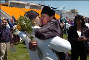 Haskell Indian Nations University graduate Michelle Gauthier, of the Menominee tribe, Neopit, Wisconsin, kisses her boyfriend Kyle Bakker of the Acoma Pueblo tribe, Denver, following her Commencement ceremony Friday afternoon at Haskell Memorial Stadium.