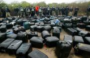 Police officers stand behind fuel containers belonging to victims Saturday, May 13, 2006 after a gas pipeline exploded on Friday, at Ilado, Nigeria. President Olusegun Obasanjo ordered increased security around Nigeria's pipelines following a gasoline conduit explosion that killed up to 200 people, as rescue workers sought Saturday to finish burying the dead in mass graves.