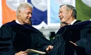 Former Presidents Bill Clinton, left, and George H. W. Bush smile at each other on the podium at the Tulane University Commencement in New Orleans on Saturday May 13, 2006.