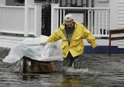 A York Beach, Maine, resident escorts a canoe filled with belongings through a flooded street outside his house. Torrential rain washed out roads and forced some people from their homes early Sunday.