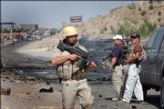 Foreign security guards stand near the scene where a car bomb exploded in Herat, in western Afghanistan. Suicide attackers detonated car bombs Thursday in two Afghan towns, Herat and Kabul, killing an American working on a counternarcotics project and an Afghan civilian, officials said.