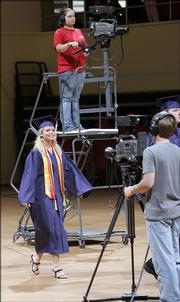 Montgomery Central High School graduate Rebecca Brit walks between cameras being used to broadcast the graduation in Clarksville, Tenn. Seven high schools near Fort Campbell, the home of the Army's 101st Airborne Division, are broadcasting their graduation ceremonies live online for family members stationed overseas. Montgomery Central's ceremony was Friday.