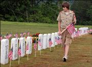 Trey Klouda of Boy Scout Troop 241 of Canton, Ga., checks flags the group placed at grave markers Saturday in the new Georgia National Cemetery in Canton.