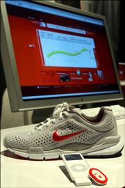The Nike Air Zoom Moire is pictured alongside an iPod, the Nike+iPod Sport Kit and a computer screen displaying the Nikeplus.com Web site.