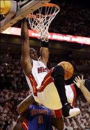 Miami's Dwyane Wade hangs onto the rim after dunking against the Detroit Pistons. The Heat won Game 4, 89-78, Monday in Miami.