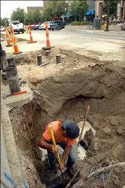 Gary Jesseph, of Nowak Construction, clears away dirt and mud from around a leak in a waterline. Jesseph later applied a clamp to secure the fire protection line Monday in the 700 block of Massachusetts Street.