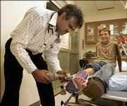 Dr. Hassan Shafeeq removes a cast from Parker Crum's ankle at the Meade District Hospital in Meade. Shafeeq, a native of the Maldives, is one of several dozen foreign-born physicians serving rural Kansas communities under the J-1 visa waiver program.
