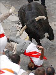 A runner falls after being hooked by a bull's horn during a San Fermin bull run in Pamplona, Spain, in 2004.