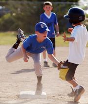 Rookie Baseball player Aric Trent of the Flame Hawks tags out Jets player Hunter Sharp during a game on Wednesday at the Youth Sports Inc.