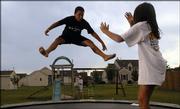 Morgan Thevarajoo, center, 11, and his sister Hannah, 9, bounce around on their backyard trampoline as their mother Kim Thevarajoo, back, cleans their play area. After living in Lawrence for about eight years, the family moved to Eudora in 2003 because houses are more affordable there and the school district is smaller. A new Census Bureau report shows that Eudora's population continues to climb, while the number of people living in Lawrence dropped slightly.