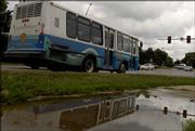 The number of people riding the T is climbing, thanks to higher gas prices and greater community acceptance. The No. 6 T Bus is reflected in a pool of water as it heads downtown Thursday afternoon.