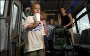 Lawrence youngster Luke Dunlap, 5, drinks his soda Thursday while he waits for the bus driver to open the side door as his mother, Julie Dunlap, corrals his sisters. The Dunlaps rode the T for the first time Thursday on their way home from downtown Lawrence. Records released by the Lawrence Transit System show that ridership through the first six months of the year is up about 15 percent from last year.