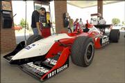 Indy Racing League's Vitor Meira, left, touches the tread of an Indy car parked at Casey's General Store in Basehor. Panther Racings' Meira spoke about the benefits of ethanol at a news conference Thursday in Basehor. Next year, the IRL will use 100 percent ethanol fuel.