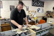 Jeffery Howlett, owner of Kansas Firearms Specialties in Tonganoxie, cleans off a handgun Thursday in his store. A new law, which takes effect Saturday, prohibits weapons in businesses that post signs stating that guns aren't allowed.