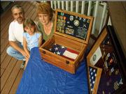 Marty and Tina Trumble, who married while they were in the Navy, keep two flags with special meaning at their house - the one at left was flown at City Hall to honor Marty's retirement, and the one at right was flown on the island of Diego Garcia to honor Tina's retirement. The Lawrence couple are pictured with their 8-year-old daughter, Katie.