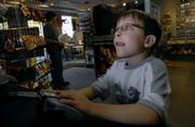 Video game enthusiast Jake Whitebread, 7, Eudora, gets wrapped up playing a Nintendo Game Cube on Thursday afternoon at Game Guy in downtown Lawrence. Jake visited the store with his older brother Tyler Whitebread, 14, who says that he and his brother frequently play video games or spend time on their computer for a few hours a day.