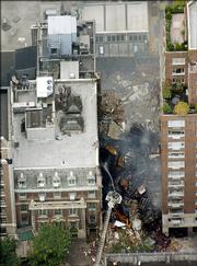New York City firefighters direct water on the remains of a collapsed building on Manhattan's Upper East Side. An explosion rocked the four-story building Monday, causing a fire and eventually a collapse, injuring at least five civilians and 10 firefighters.