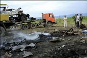 Police officers look at the wreckage of a truck and cars blown up at the site where Chechen warlord Shamil Basayev and other rebels were killed in the Ingush village of Ekazhevo. Basayev was killed Monday when a dynamite-laden truck in his convoy exploded.
