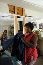 Although her home of nearly 30 years has been declared "unsafe" by city inspectors, Flora Taylor and several other family members continue to live there, including her cousin Cyrese Powell, back left. The home in the 2600 block of Bonanza Street was damaged in the March 12 microburst, but Taylor&squot;s insurance company says it was not properly built and will not pay to repair or replace the faulty support beam seen above Taylor and Powell.