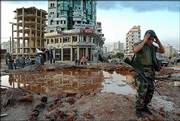 A Lebanese soldier stands near a crater after Israeli airstrikes Friday at the main Mar Mikhail crossroads in southern Beirut, Lebanon. Israel has widened its offensive on Lebanon, with fighter bombers blasting the airport for a second day and residential buildings in the southern suburbs of the capital. The blasts ignited fuel storage tanks and cut the main highway to Syria.