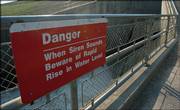 Signs posted along the overlook of the spillway at Perry Lake warn visitors of rapidly rising water levels when the dam is opened. The Army Corps of Engineers began draining water from the reservoir on Wednesday to aid barge traffic on the Missouri River.