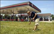 Jason Roy reads the water meter Wednesday at the Miller Mart on W. Sixth Street. The store has been closed since reserve gas tanks floated up from rainfall in September.