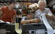 Douglas County voting clerk Elizabeth Ross, Lawrence, left, watches as supervising judges Don McDowd, Lawrence, and Nadine Larrick, Wellsville, remove a receipt of recorded votes from one of the new voting machines Thursday morning at Professional Moving and Storage warehouse. County voting officials tested the new electronic voting machines in preparation for Tuesday's primary.