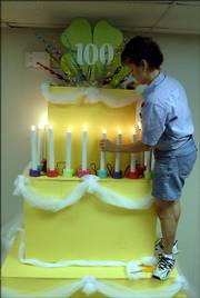 Twilla Brown helps create a birthday cake display to celebrate 100 years of 4-H in Kansas. Brown, a 4-H Food superintendent, was among those preparing Friday for the Douglas County Fair. See page 3B for fair schedule highlights.