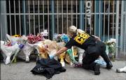 A crime scene investigator rearranges flowers on Saturday in front of the Jewish Federation Building in Seattle so that investigators can close the gate at right after examining the crime scene. Officials stepped up security at both synagogues and mosques Saturday as authorities investigated a shooting at the building that killed an employee and wounded five others, including a pregnant woman.