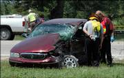 Emergency crews inspect a car that was involved in a two-car accident at Baldwin Junction, the intersection of US 56 and US 59 west of Baldwin.