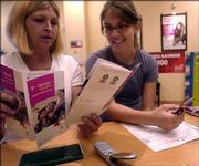Toni Retonde, left, with her daughter, Jennifer Holladay, read over the details of a T-Mobile wireless service plan at a distributor downtown. New cell phone technology is available that allows parents to track their children via the Internet and GPS devices in their phones.