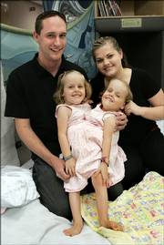 Jake and Erin Herrin pose with their conjoined twin daughters, Kendra, left, and Maliyah, outside their hospital room Thursday at Primary Children's Medical Center in Salt Lake City. The twins say they like being together all the time, but are excited to have separate lives.