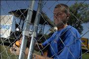 Zach Nettleton, Blue Springs, Mo., of National Construction Rentals, works to secure a fence beside one of the concert stages Friday afternoon at Burcham Park.
