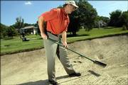 Dick Stuntz, general manager of Alvamar golf course, demonstrates the proper etiquette for raking a sand bunker.
