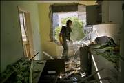 An Israeli policeman searches the kitchen of an apartment Saturday in the northern Israeli town of Kiryat Shmona after it was hit by a Hezbollah rocket. Three Israeli Arab women were killed in one of many attacks as dozens of Hezbollah rockets slammed into communities across northern Israel.