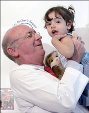Dr. Thomas Balkany holds 3-year-old Amina, of Iraq, during a news conference Friday in Miami. Amina arrived last Sunday from Jordan to receive a cochlear implant that will restore the deaf girl's hearing.