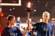 Drew Miller, Iola, at left, and Richie Wagstaff, Prairie Village, pass the torch during Traditions Night 2005 in Memorial Stadium. Both are fifth-generation Jayhawks. This year's Traditions Night will be from 8 p.m. to 9 p.m. Monday, when students will learn Jayhawk songs, cheers and the alma mater.