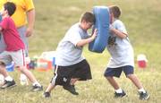 Fouth-graders Jake Holiday, left, and Trip Wright go through a tackle drill during the Lawrence Youth Football practice for the Hurricanes at Dad Perry Park.