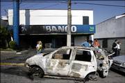A burned car remains in front of a bank that was attacked Monday in Sao Paulo, Brazil. Assailants sprayed gunfire at police, blew up explosives outside government buildings and torched buses and bank branches Monday in a new wave of attacks.