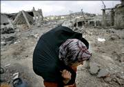 A member of the Lebanese Srour family (first name not given) carries some of her belongings after she returned to her family's house Saturday in the southern border village of Aita al-Shaab, Lebanon. She discovered that the home was in rubble, destroyed during the monthlong Israeli forces' offensive.