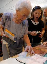 Arlene Lawson, left, and Chelsea Vaughn, 11, both of Eudora, view items found in a 1921 cornerstone time capsule from the Eudora United Methodist Church. Among the water-damaged items revealed Sunday was a church roster, where Lawson found several of her Westerhouse relatives listed.