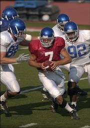 Kansas quarterback Adam Barmann is hounded by KU defenders during a scrimmage. The Jayhawks practiced Wednesday at Memorial Stadium as part of Fan Appreciation Day.