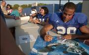 Kansas senior running back Jon Cornish autographs posters and footballs at the end of Fan Appreciation Day. The Jayhawks scrimmaged Wednesday at Memorial Stadium, then mingled on the field with fans.